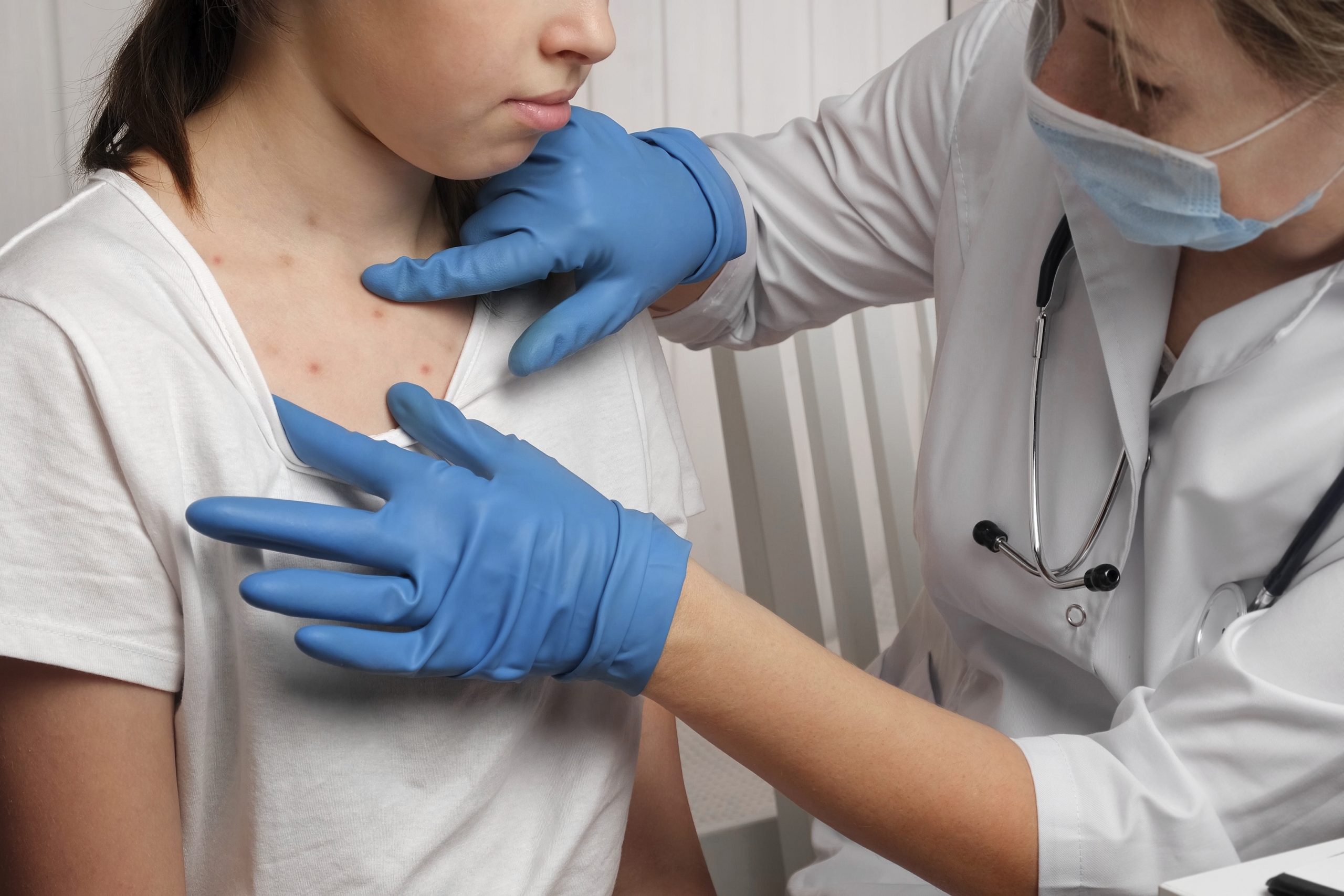 Ein Kinderarzt untersucht rote Pusteln auf der Haut eines Kindes.
